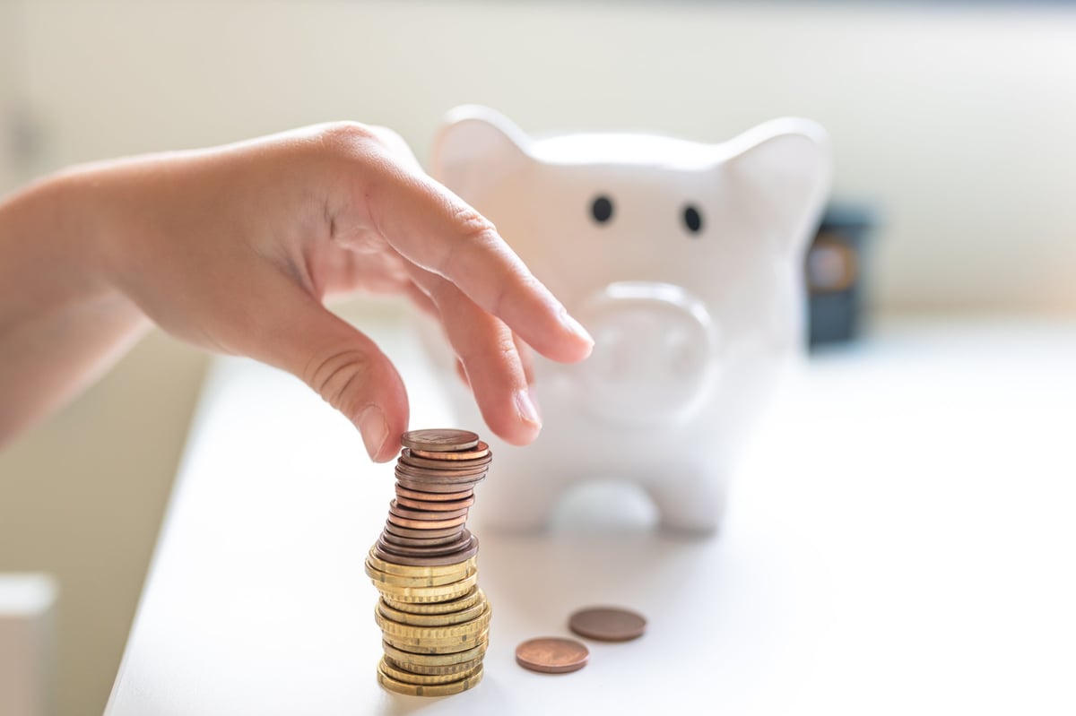 Hand inserting a coin into a piggy bank